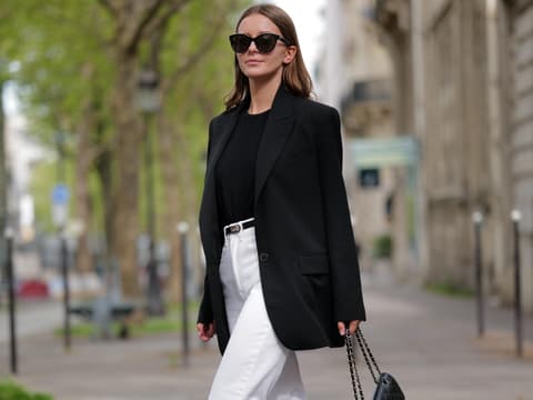Frau trägt schwarzen Blazer und weiße Jeans
