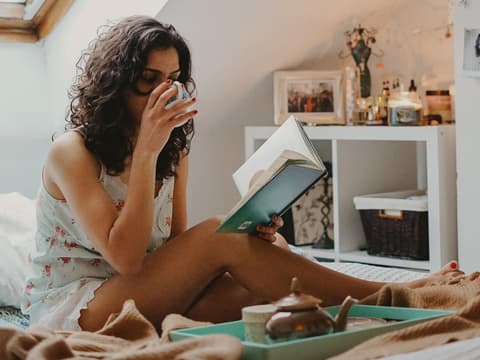 Frau liest Buch mit Kaffee in der Hand