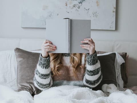 Frau liest Buch im Bett
