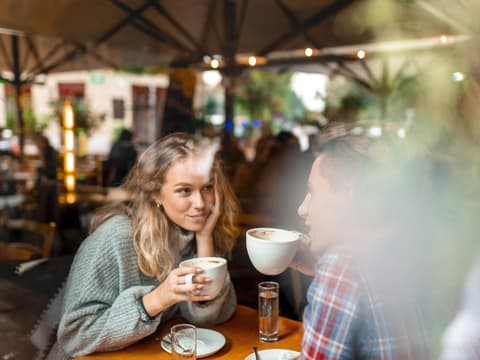 Mann und Frau sitzen sich gegenüber und trinken Kaffee